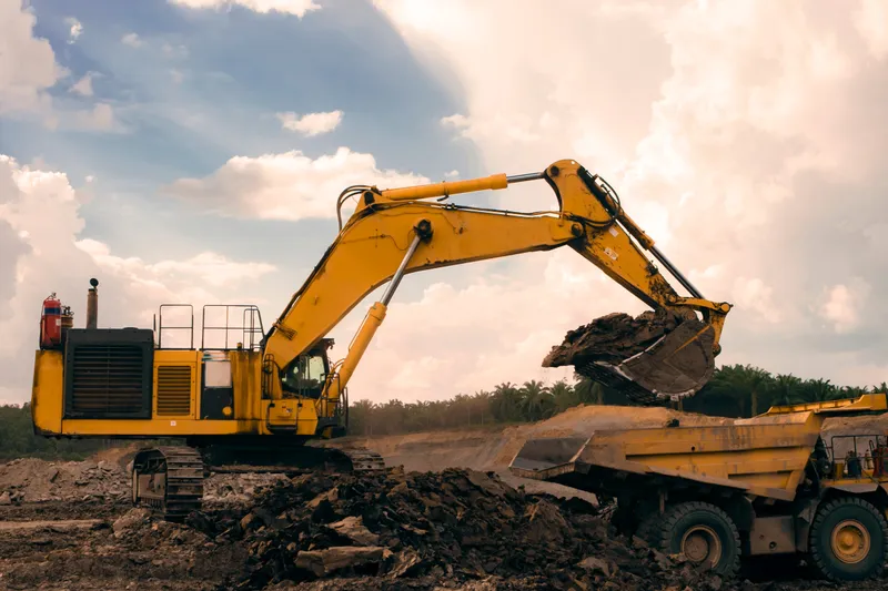 Excavadora amarilla cargando tierra en un camión